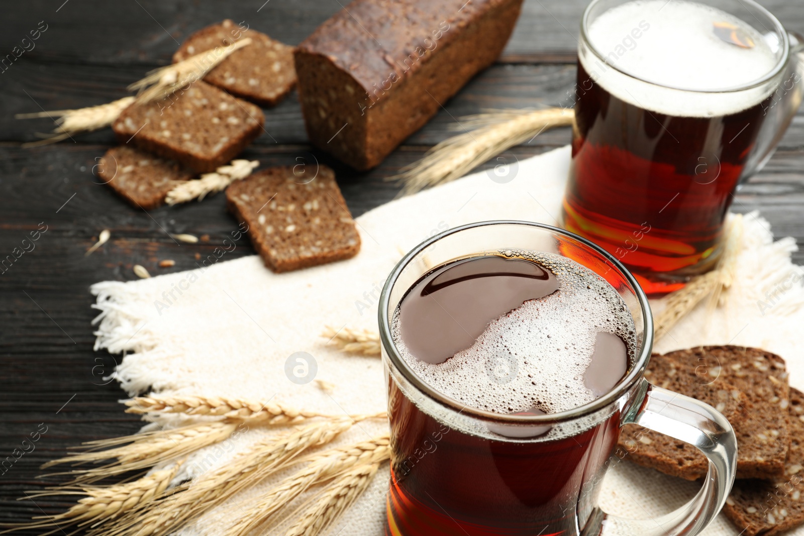 Photo of Mugs of delicious kvass, spikes and bread on table