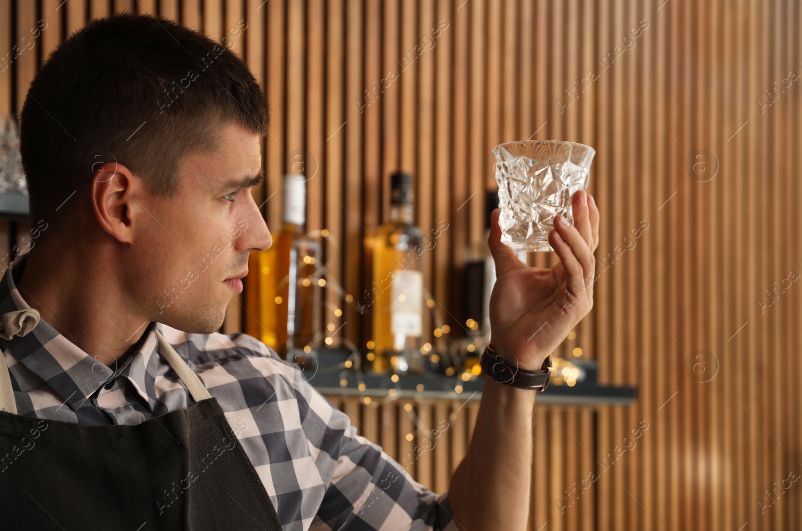 Photo of Male bartender wiping whiskey glass at workplace