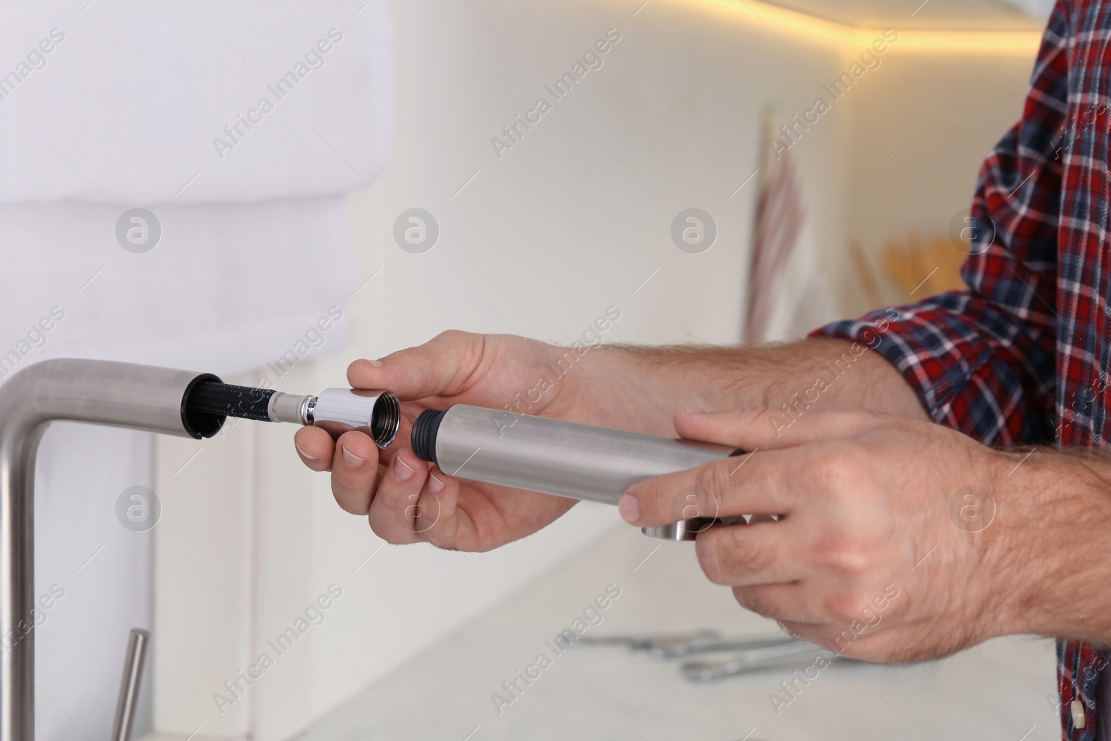 Photo of Man repairing water tap in kitchen, closeup