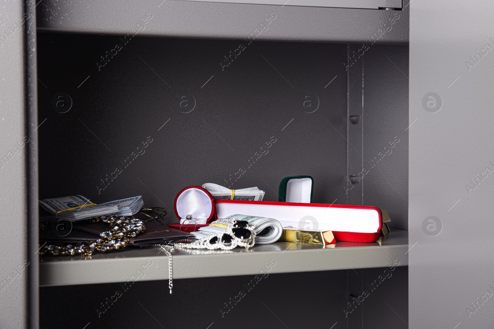 Photo of Open steel safe with money, gold bars and jewelry, closeup