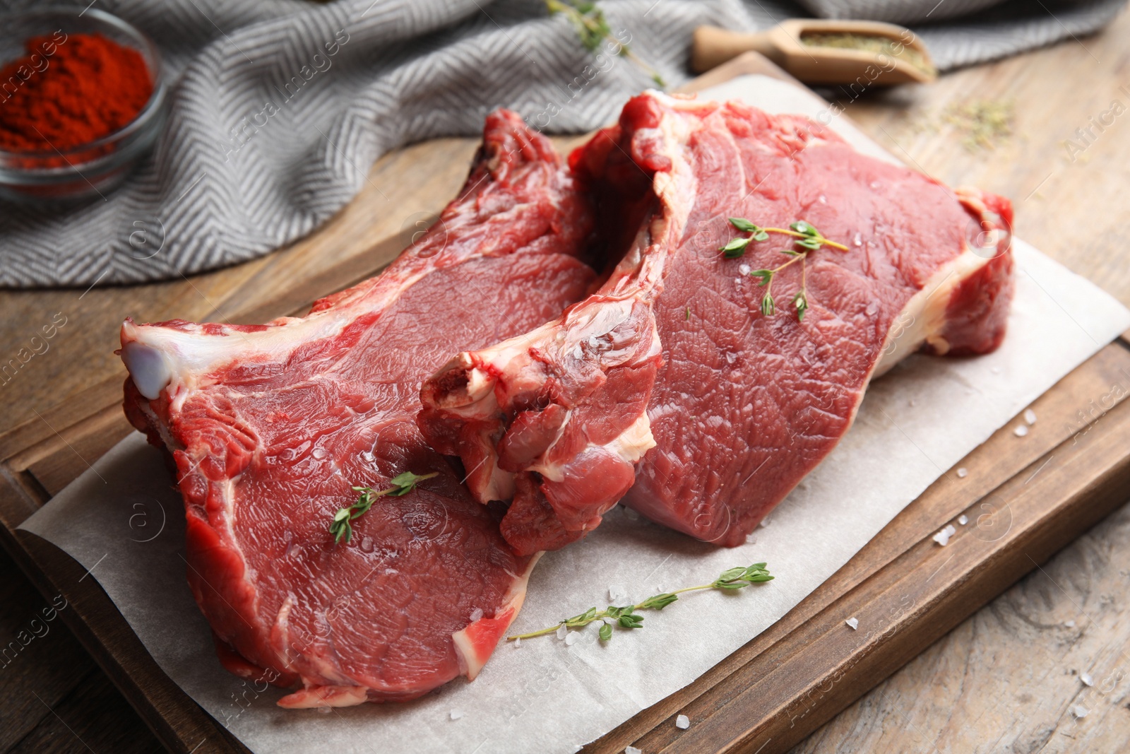 Photo of Fresh raw beef cut with thyme and salt on wooden table, closeup