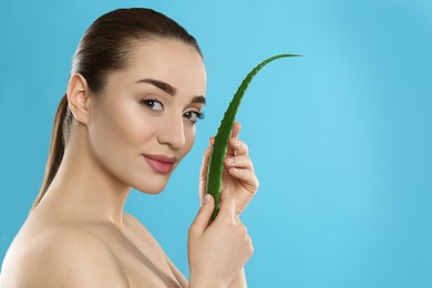 Photo of Young woman with aloe vera leaf on light blue background. Space for text
