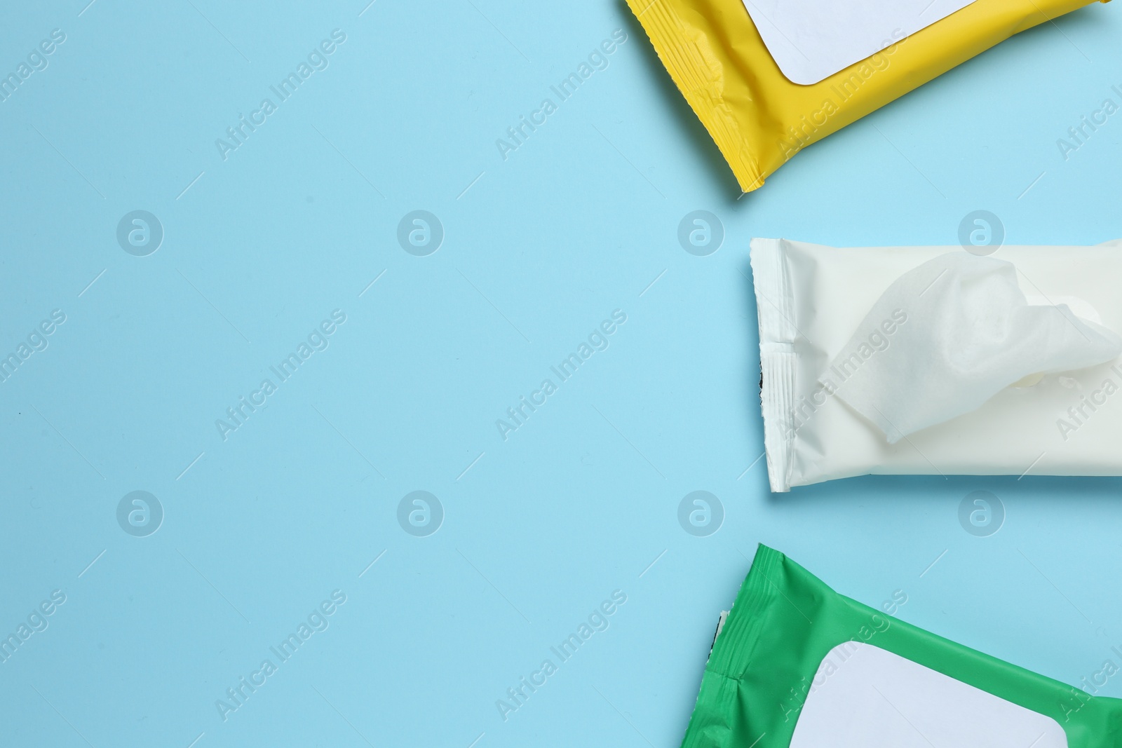 Photo of Wet wipes flow packs on light blue background, flat lay. Space for text