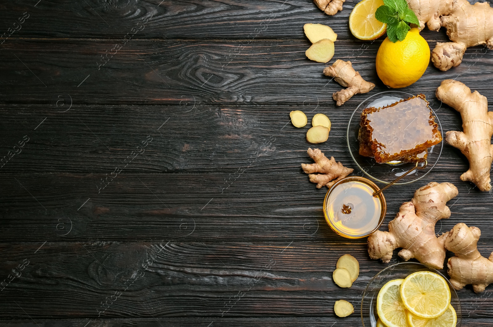 Photo of Ginger and other natural cold remedies on black wooden table, flat lay. Space for text