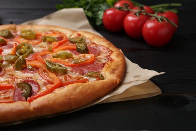 Delicious pizza Diablo and ingredients on black wooden table, closeup