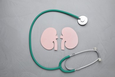 Photo of Paper cutout of kidneys and stethoscope on grey table, flat lay