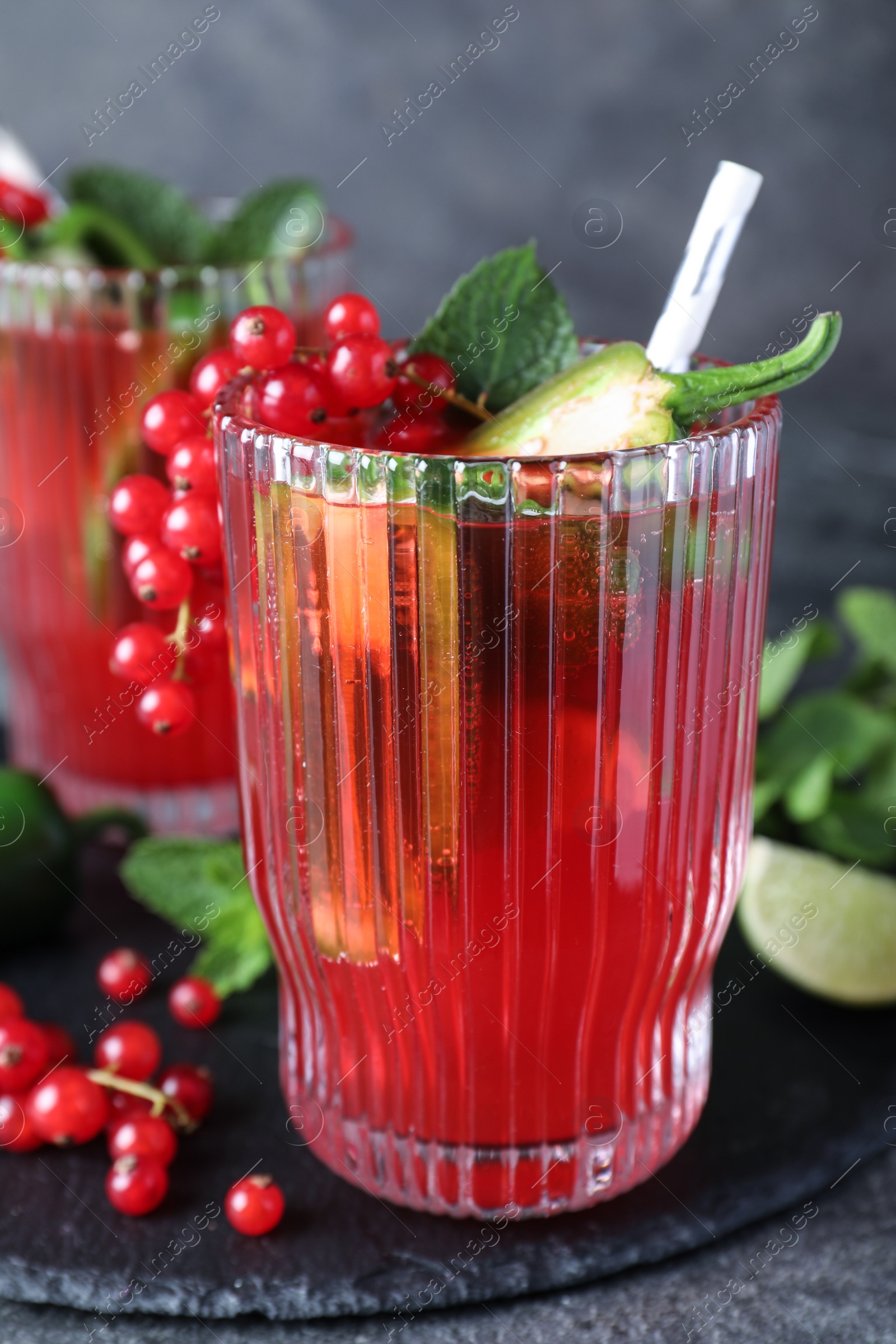 Photo of Glasses of spicy red currant cocktail with jalapeno and mint on grey table, closeup