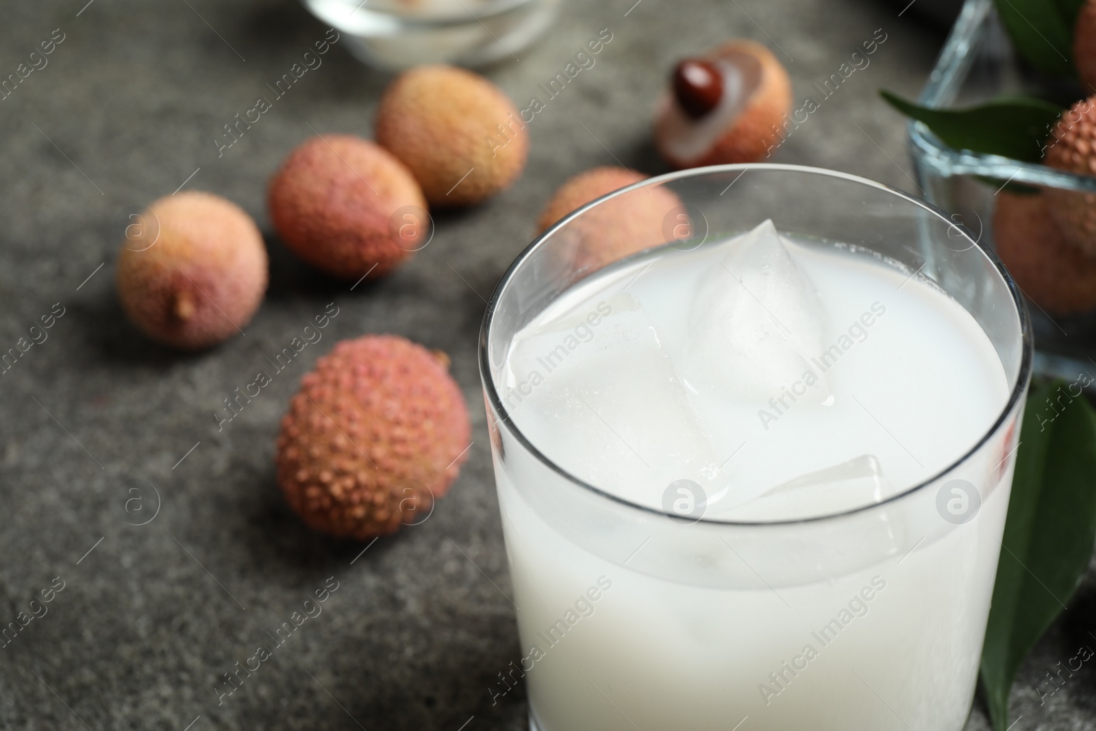 Photo of Fresh lychee juice on grey table, closeup