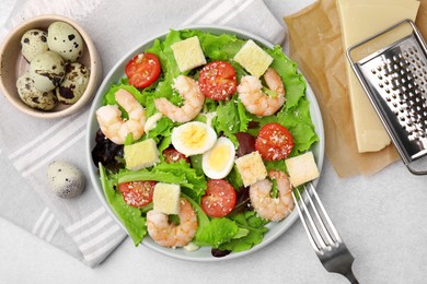 Photo of Delicious Caesar salad with shrimps and fork served on light table, flat lay