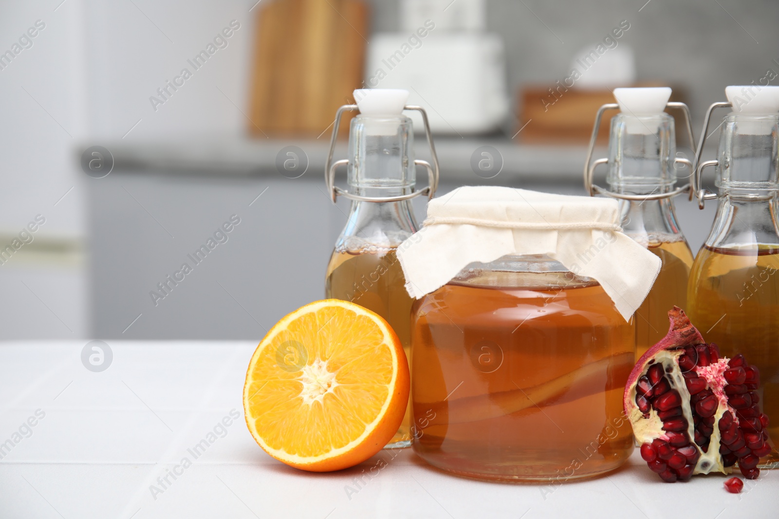 Photo of Homemade fermented kombucha and fresh fruits on white table in kitchen. Space for text