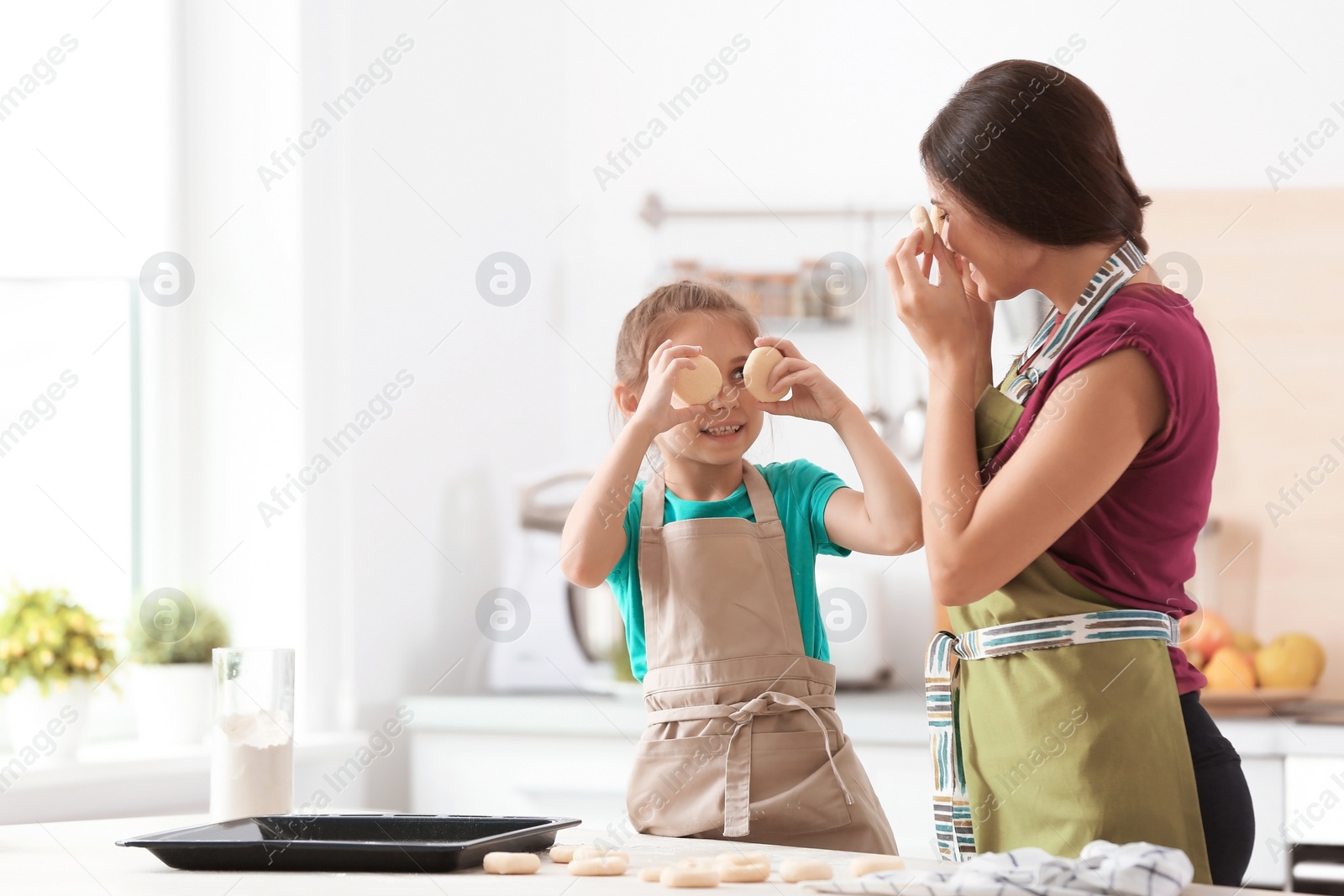 Photo of Mother and her daughter with cookie dough in kitchen