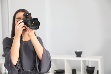 Photo of Young woman with professional camera in photo studio. Space for text