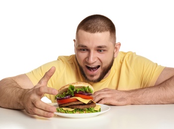 Young hungry man and tasty burger on white background