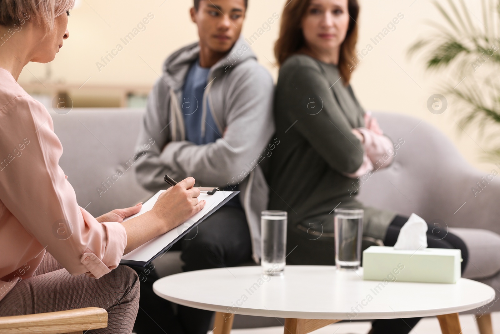 Photo of Psychotherapist working with African-American teenage boy and his mother in office, closeup