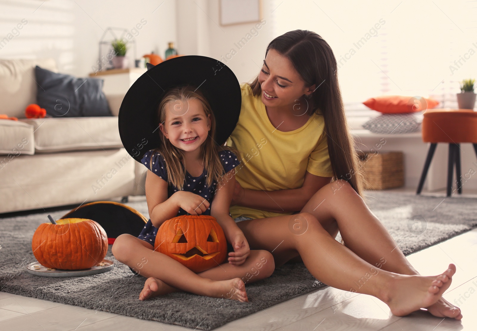 Photo of Mother and daughter with pumpkin jack o'lantern at home. Halloween celebration