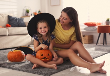 Photo of Mother and daughter with pumpkin jack o'lantern at home. Halloween celebration