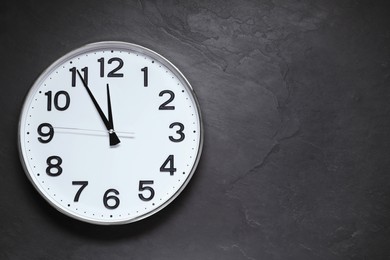 Clock showing five minutes until midnight on black table, top view with space for text. New Year countdown