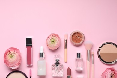 Flat lay composition with different makeup products and beautiful spring flowers on pink background. Space for text