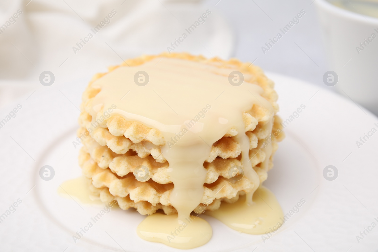 Photo of Tasty waffles with condensed milk on plate, closeup