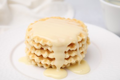 Photo of Tasty waffles with condensed milk on plate, closeup