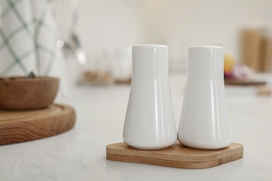 Photo of Ceramic salt and pepper shakers on white countertop in kitchen, space for text