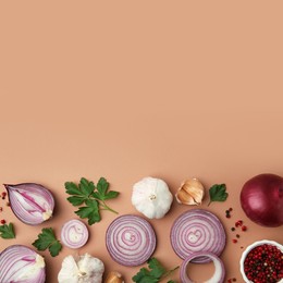 Fresh red onions, garlic, parsley and spices on beige background, flat lay. Space for text