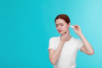 Woman using ear drops on light blue background. Space for text