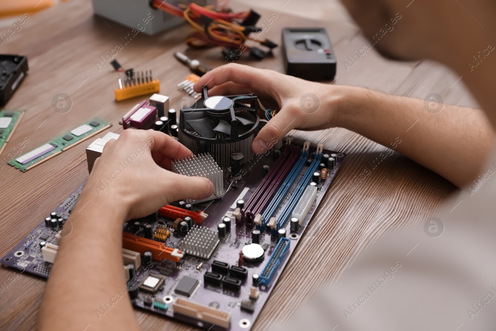 Photo of Male technician repairing motherboard at table, closeup