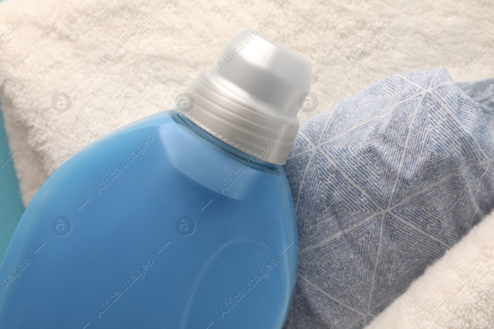 Photo of Bottle of fabric softener and on towels, top view