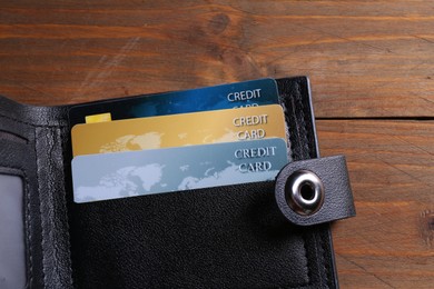 Photo of Credit cards in leather wallet on wooden table, top view