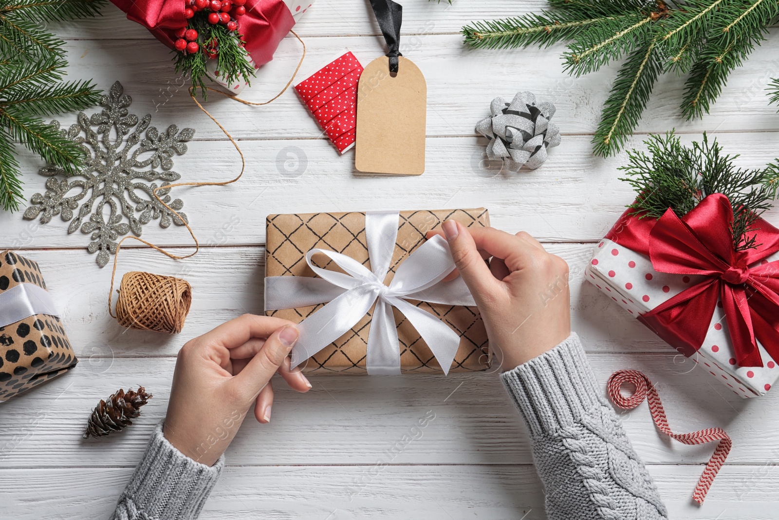 Photo of Woman wrapping Christmas gift at wooden table, top view