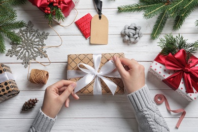 Woman wrapping Christmas gift at wooden table, top view