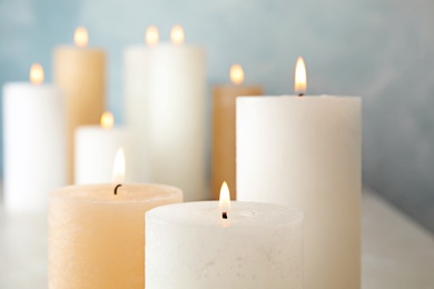 Burning candles on table against color background, closeup