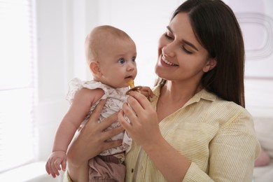 Photo of Happy mother giving pacifier to her cute little baby at home