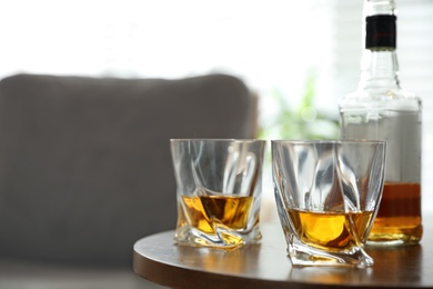 Photo of Glasses and bottle of whiskey on table indoors. Space for text