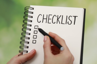 Woman filling Checklist against blurred background, closeup