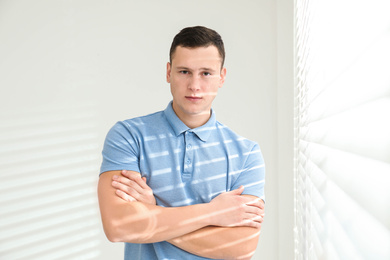 Handsome young man near window at home