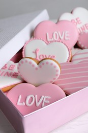 Photo of Delicious heart shaped cookies in box on white table, closeup