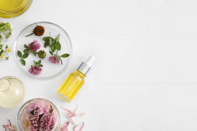 Flat lay composition with cosmetic oil and flowers on white table, space for text