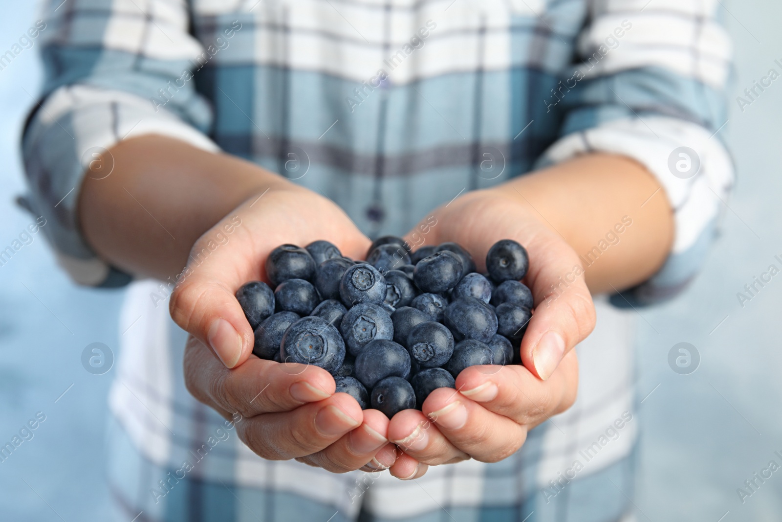 Photo of Young woman holding tasty ripe blueberries, closeup