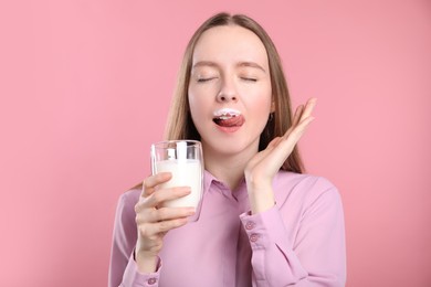 Photo of Cute woman with milk mustache holding glass of tasty dairy drink on pink background
