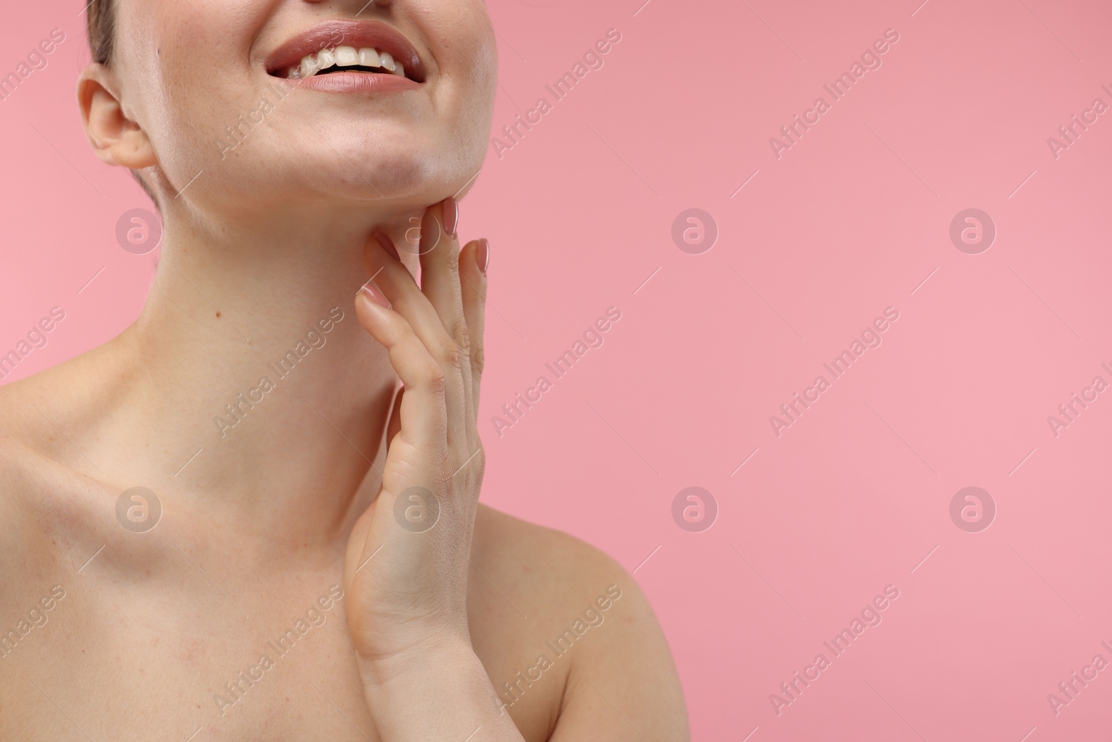 Photo of Smiling woman touching her neck on pink background, closeup. Space for text