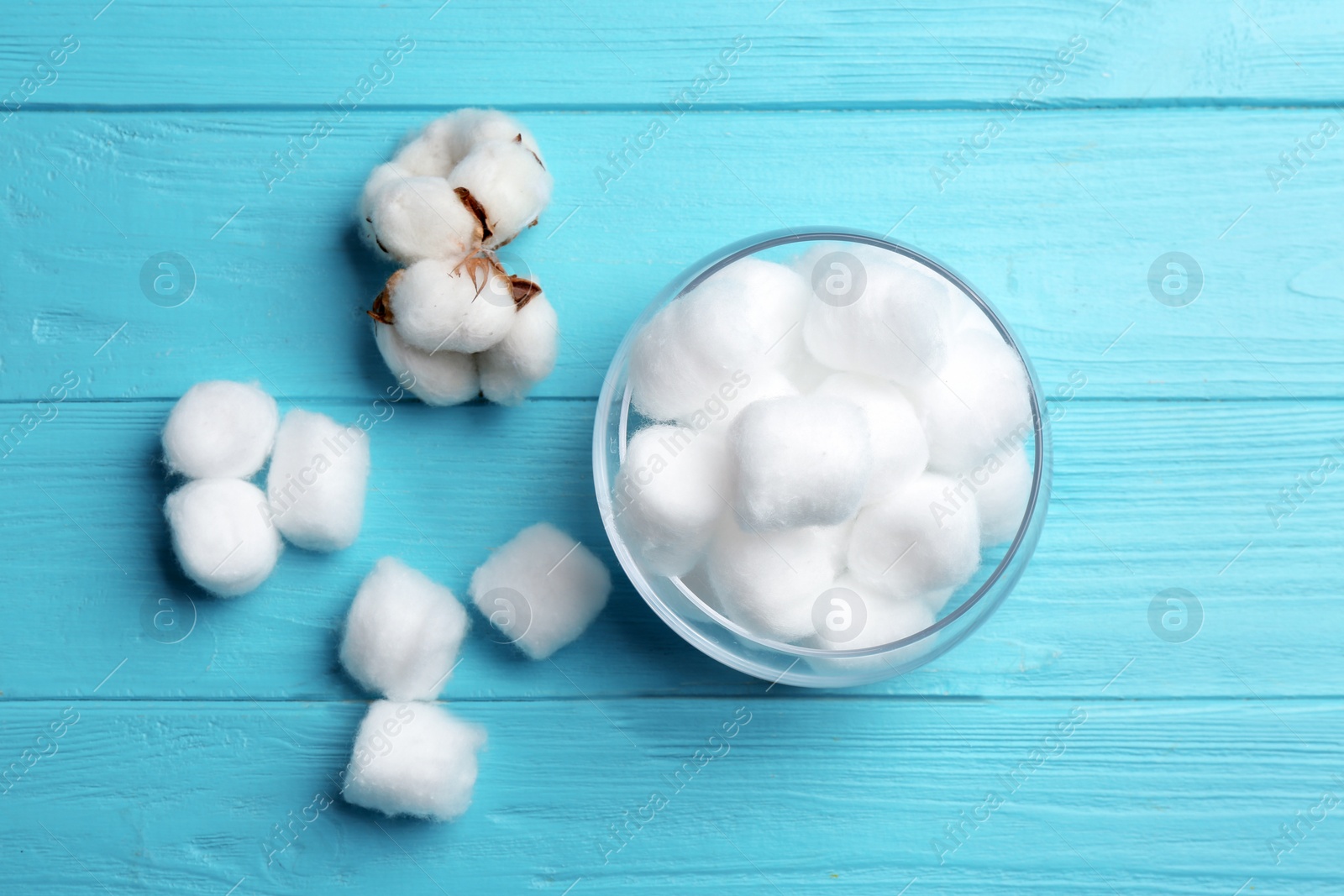 Photo of Fluffy cotton balls and flowers on color wooden background, flat lay