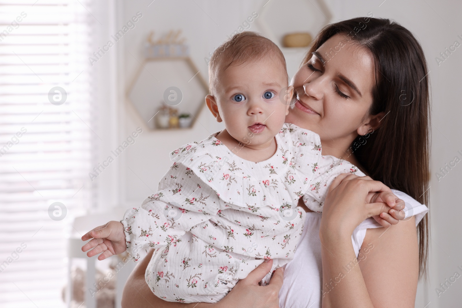 Photo of Happy young mother with her baby daughter in nursery