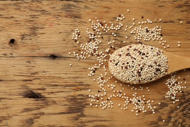 Photo of Spoon with raw quinoa seeds on wooden table, top view. Space for text