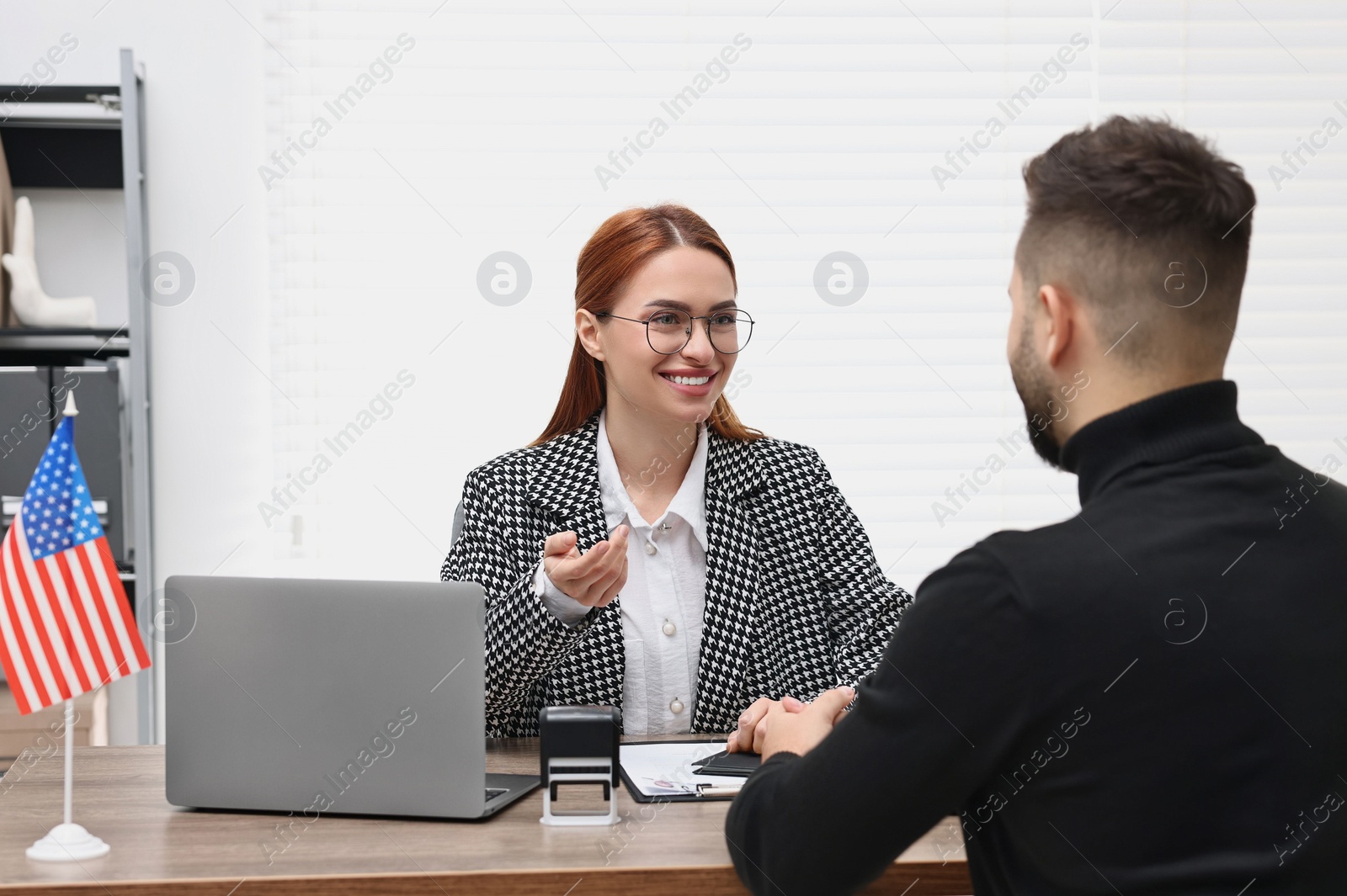 Photo of Smiling embassy worker consulting man about immigration to United States of America in office
