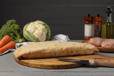 Photo of Delicious strudel with chicken and vegetables on grey wooden table, space for text