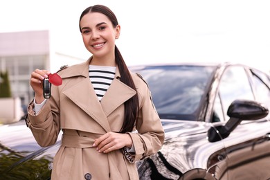 Photo of Woman holding car flip key near her vehicle outdoors