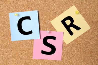 Photo of Abbreviation CSR made of paper notes on cork board. Corporate social responsibility