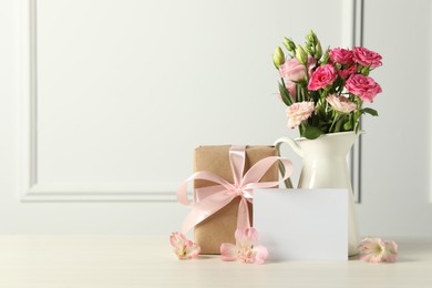 Photo of Happy Mother's Day. Gift box, blank card and beautiful flowers on white table. Space for text